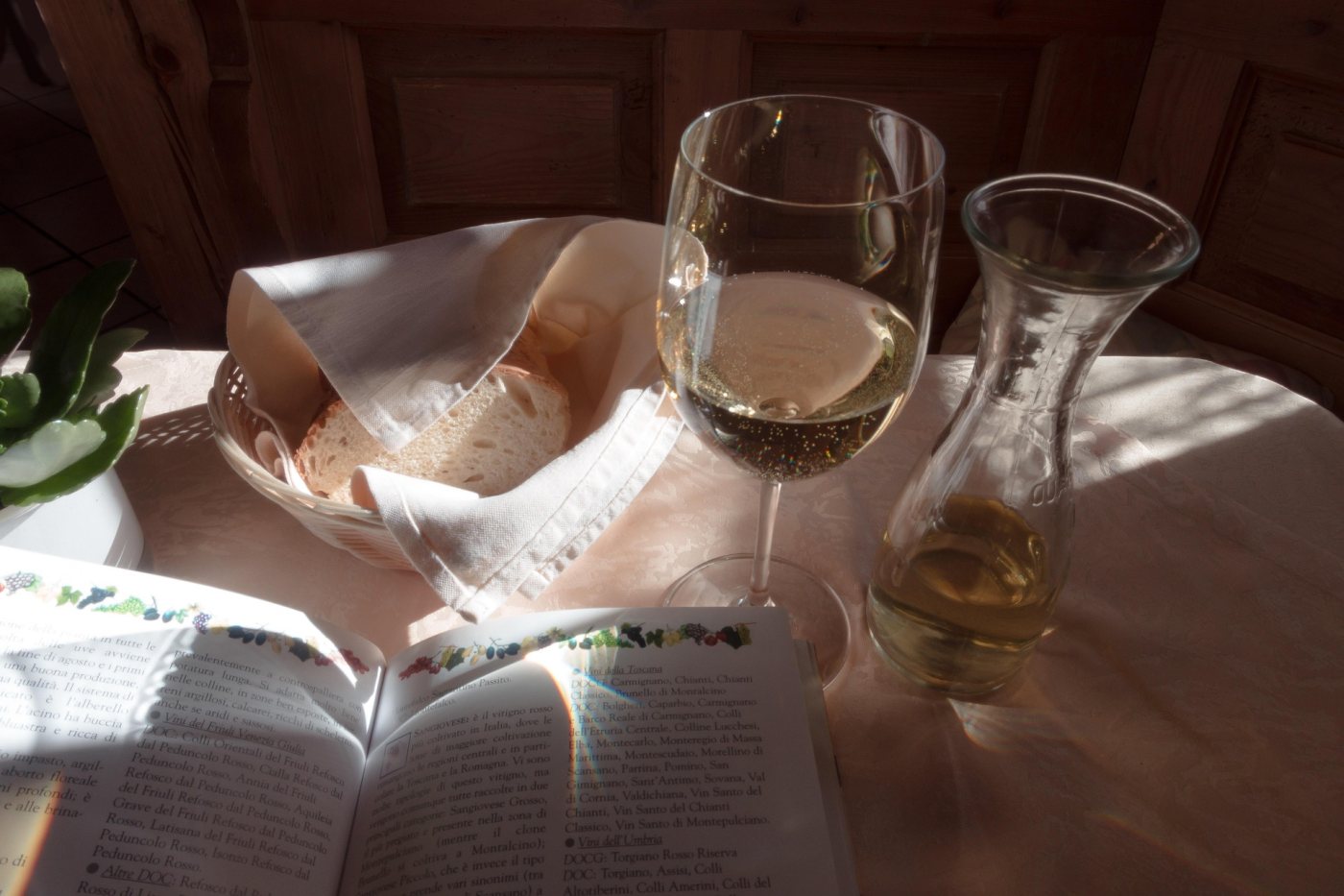 Gedeckter Tisch mit italienischem Weißwein, Brot und einem Buch über italienische Weine
